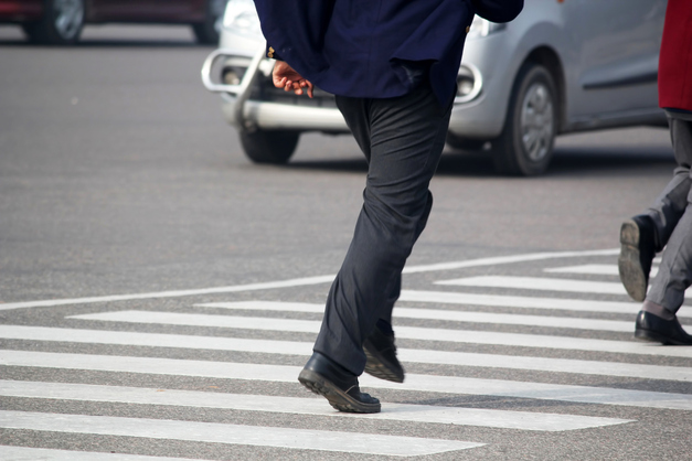 Men cross road from zebra crossing sign
