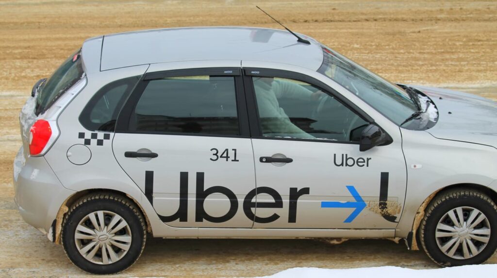Silver Uber car with logo on a dirt road, symbolizing rideshare accidents in Dallas.